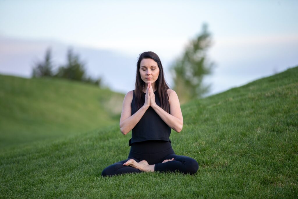 Mujer blanca de pelo negro meditando en posición de loto con los ojos cerrados